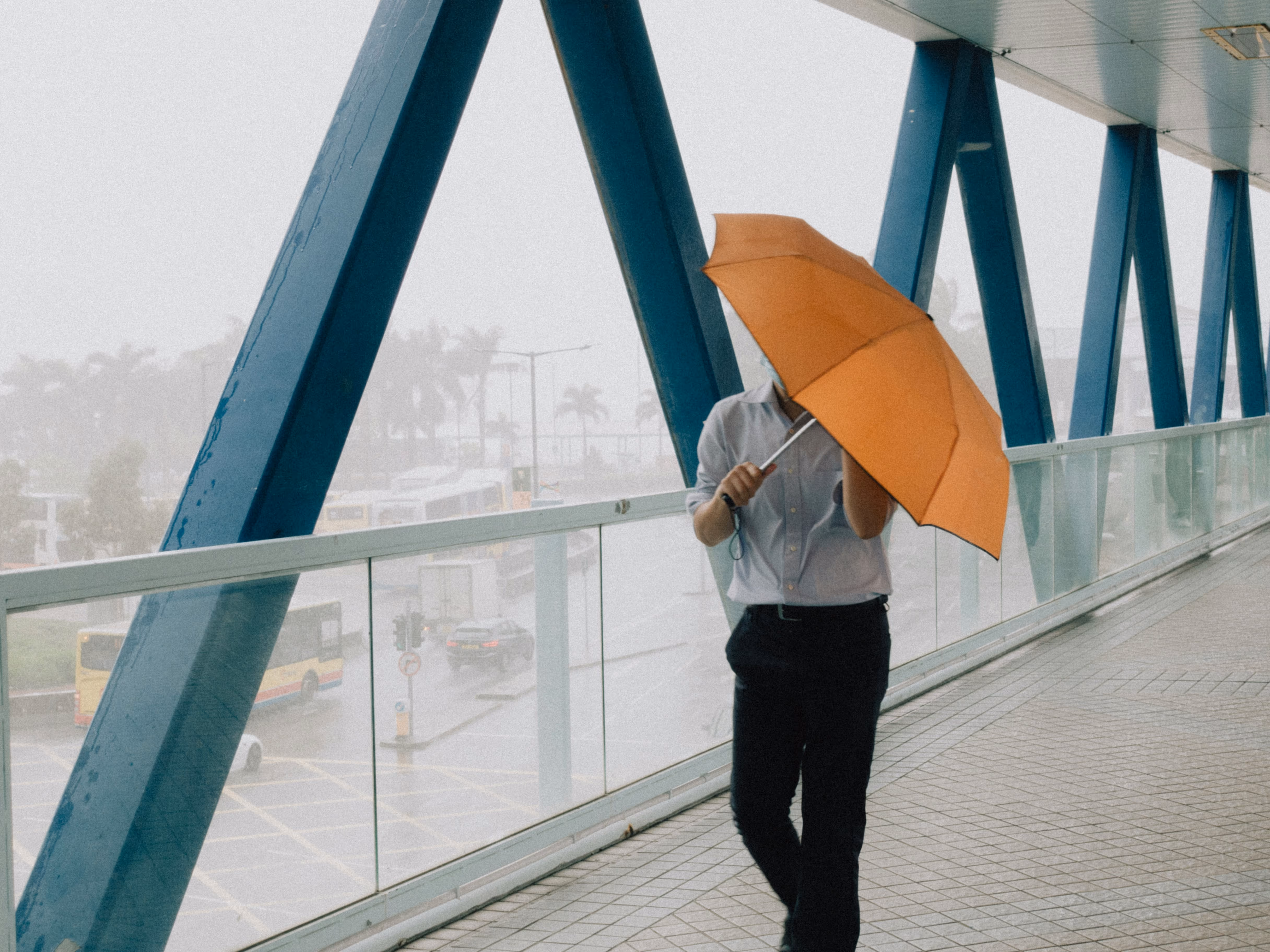 A guy in suit holding an umbrella during a typhoon day on a pedestrian footbridge in Hong Kong