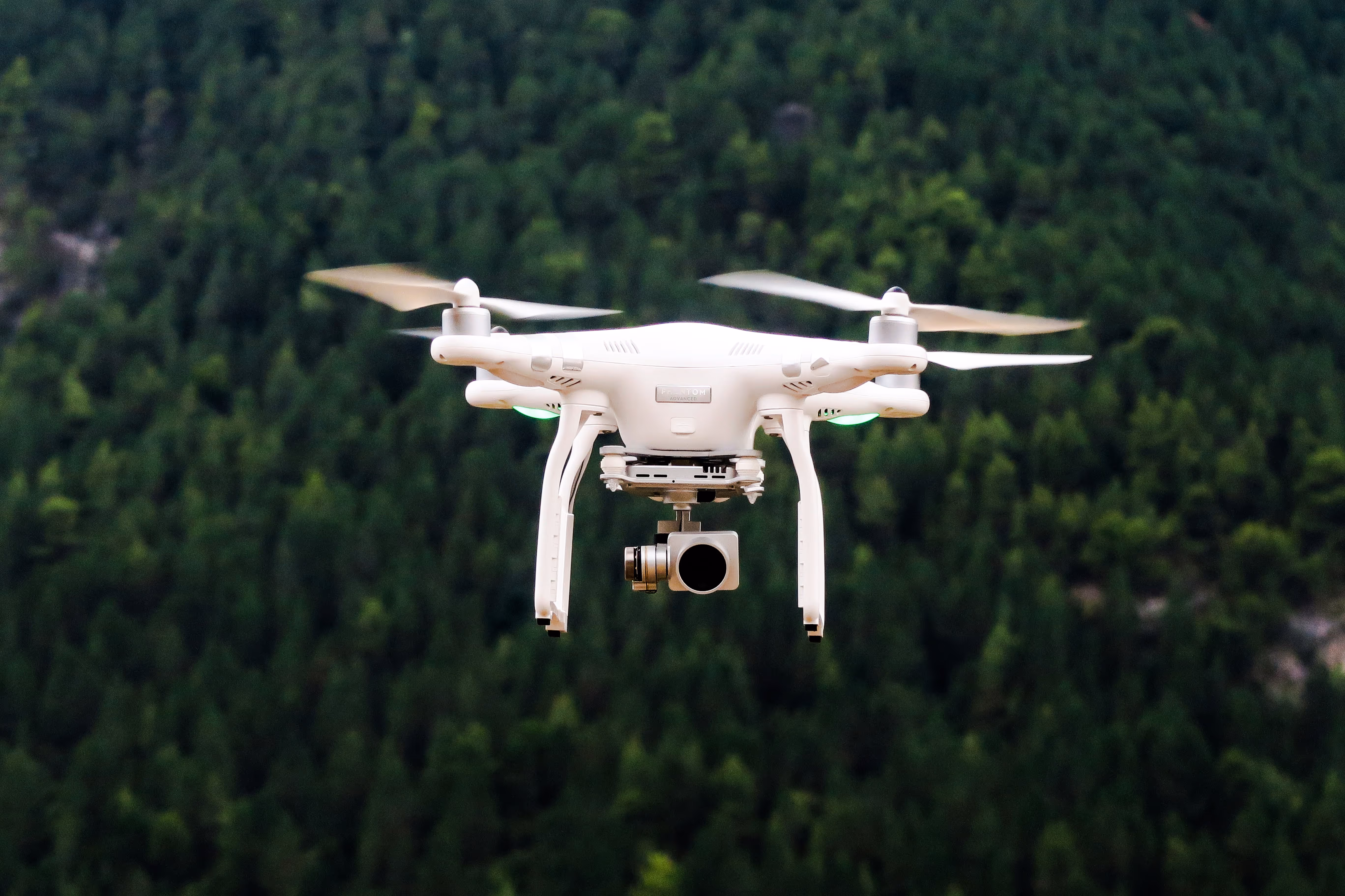 A drone with camera flying on sky with a forest background